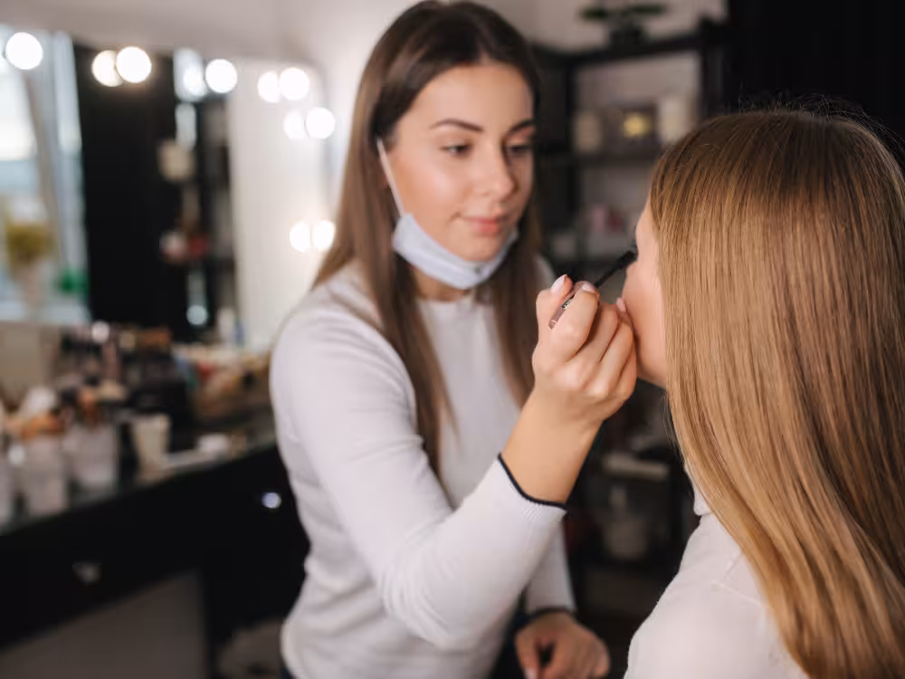 Maquiadora fazendo a maquiagem da cliente para festa de final de ano