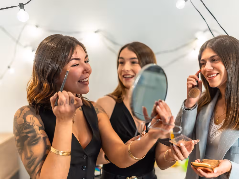 Três mulheres felizes se maquiando em uma festa de ano novo